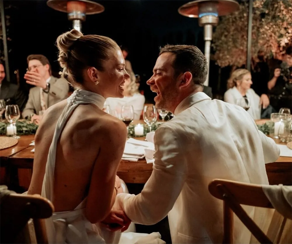 Pareja de novios riendo en la mesa de la fiesta