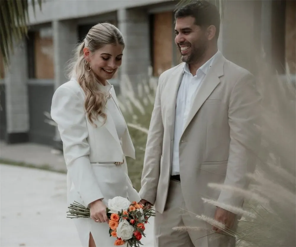 Pareja de novios de blanco frente a un edificio
